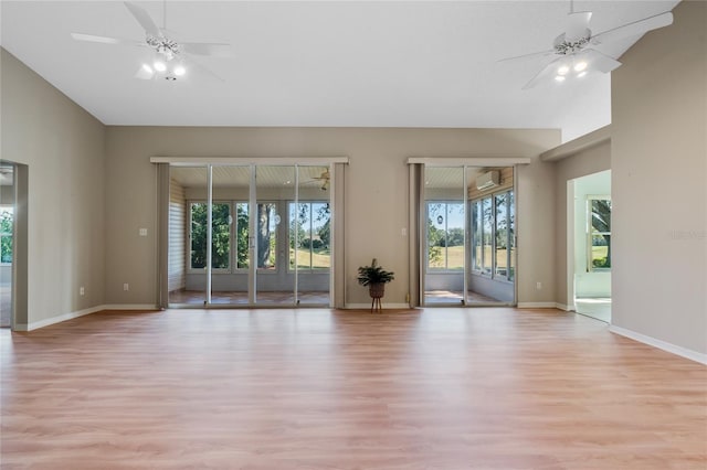 empty room with vaulted ceiling, an AC wall unit, light wood-type flooring, and ceiling fan