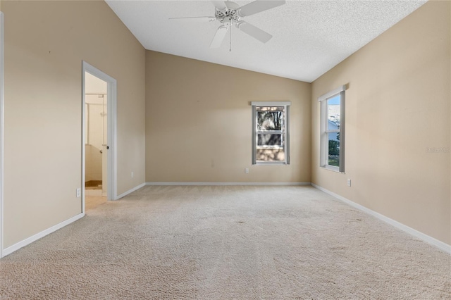 carpeted spare room with lofted ceiling, a textured ceiling, and ceiling fan