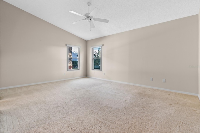 empty room with lofted ceiling, a textured ceiling, ceiling fan, and light colored carpet