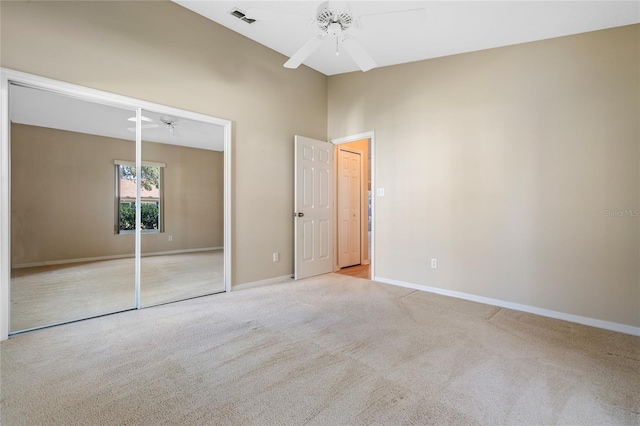 unfurnished bedroom featuring light carpet, a closet, and ceiling fan