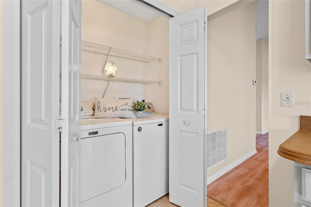 washroom with independent washer and dryer and light hardwood / wood-style floors