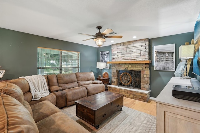 living room with a fireplace, light wood-type flooring, and ceiling fan