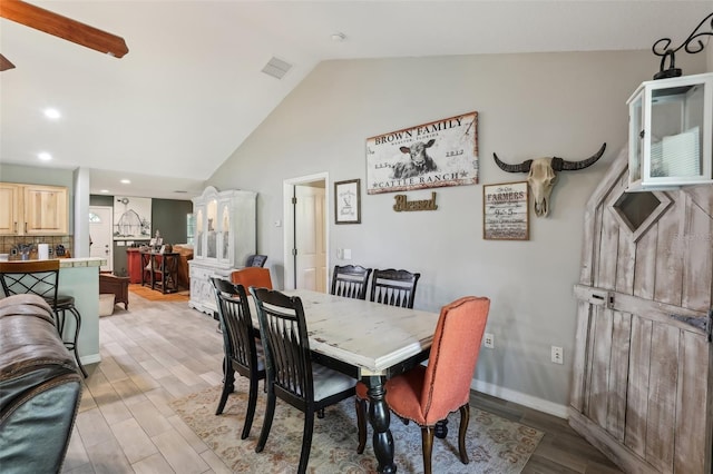 dining room with vaulted ceiling and light hardwood / wood-style floors