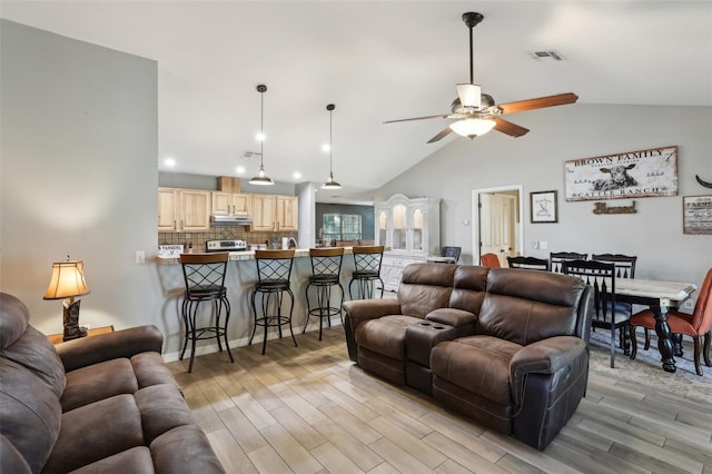 living room featuring ceiling fan, vaulted ceiling, and light hardwood / wood-style flooring