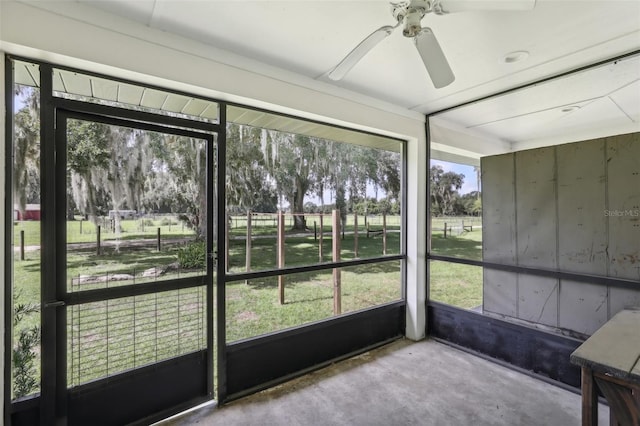 unfurnished sunroom featuring ceiling fan and a wealth of natural light