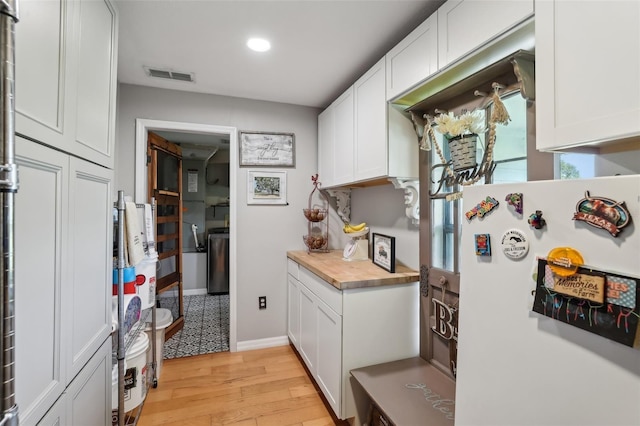 kitchen featuring white cabinets, light hardwood / wood-style flooring, white fridge, and wood counters