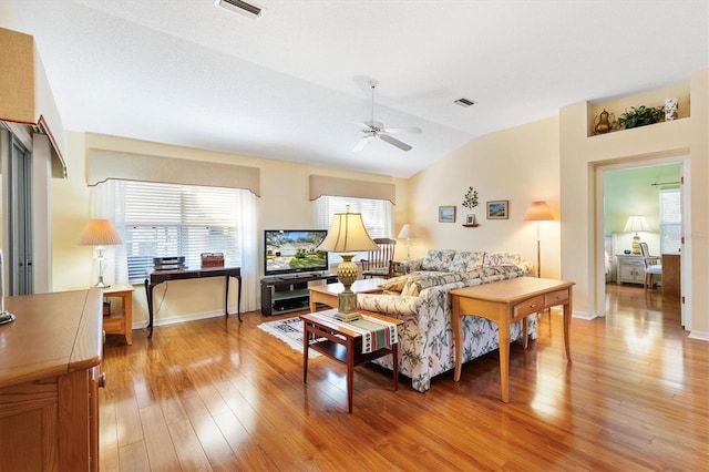 living room with ceiling fan, light wood-type flooring, lofted ceiling, and plenty of natural light