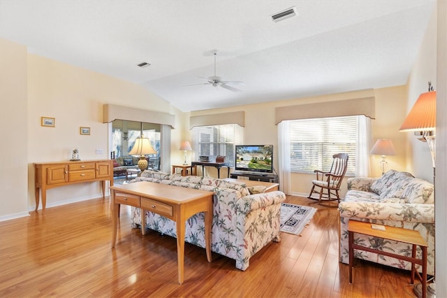 living room featuring a healthy amount of sunlight, ceiling fan, light hardwood / wood-style flooring, and vaulted ceiling