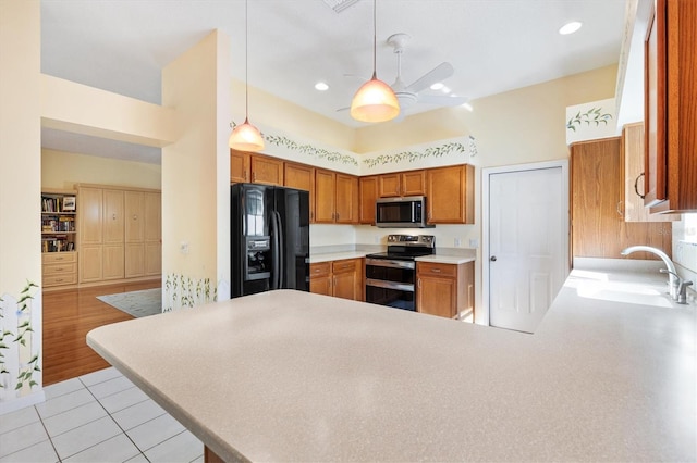 kitchen with kitchen peninsula, pendant lighting, stainless steel appliances, light tile patterned flooring, and sink