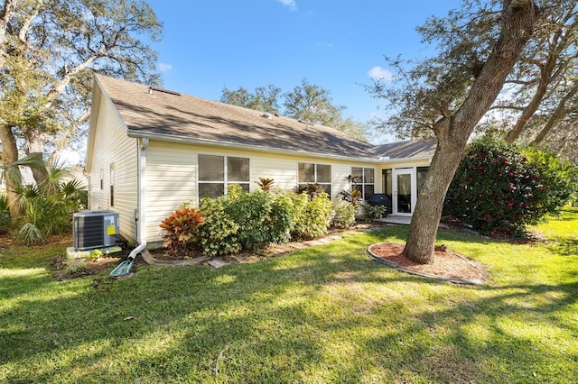 rear view of property with cooling unit and a lawn