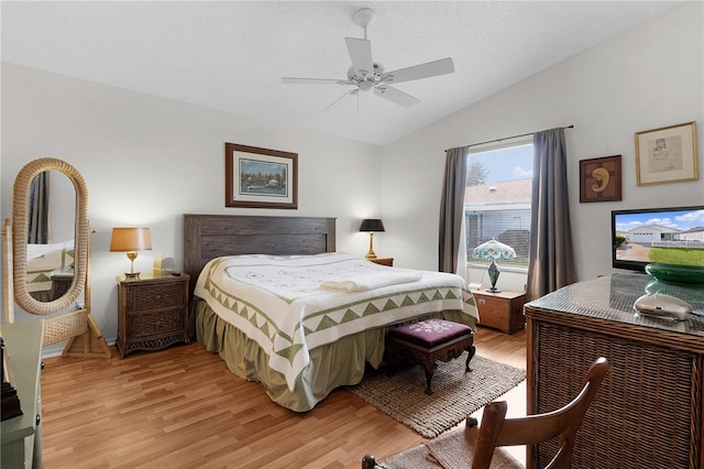 bedroom with lofted ceiling, a textured ceiling, ceiling fan, and light wood-type flooring