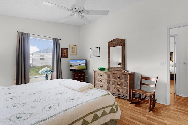 bedroom with lofted ceiling, a textured ceiling, ceiling fan, and light wood-type flooring