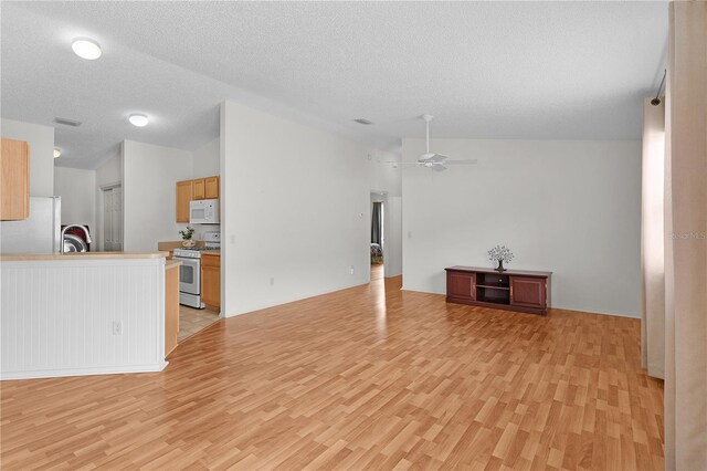 424 Rose Croft Ter, The Villages, FL 32162 - unfurnished living room featuring vaulted ceiling, light wood-type flooring, a ceiling fan, a textured ceiling, and a sink