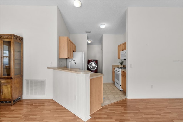 424 Rose Croft Ter, The Villages, FL 32162 - kitchen with washer / clothes dryer, white appliances, light wood-style flooring, and a peninsula