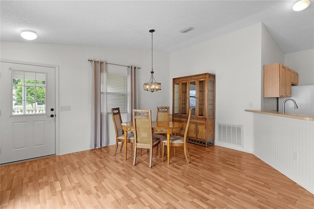 424 Rose Croft Ter, The Villages, FL 32162 - dining room featuring light wood-type flooring, a chandelier, lofted ceiling, and a textured ceiling