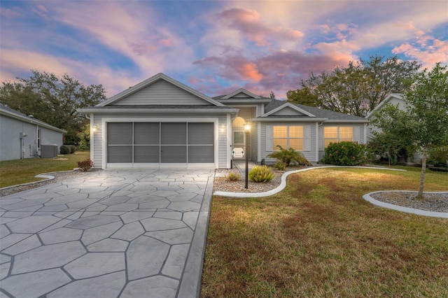 single story home with central AC unit, a garage, and a yard