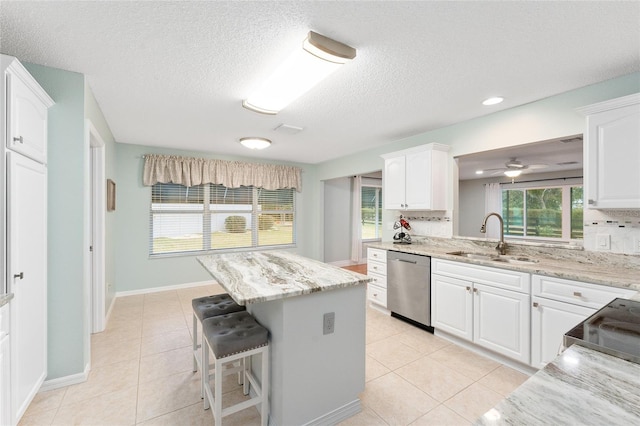 kitchen featuring white cabinets, dishwasher, a kitchen island, tasteful backsplash, and sink