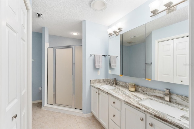 bathroom featuring vanity, a shower with shower door, tile patterned floors, and a textured ceiling