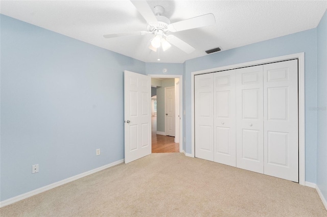 unfurnished bedroom with light colored carpet, a closet, and ceiling fan