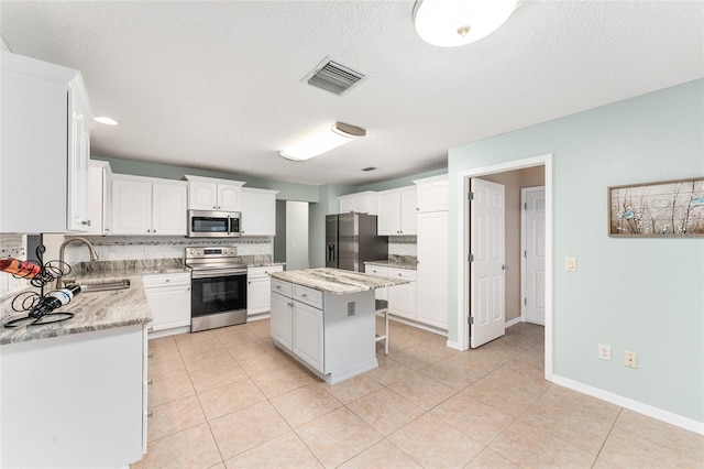 kitchen with a center island, white cabinetry, stainless steel appliances, tasteful backsplash, and sink