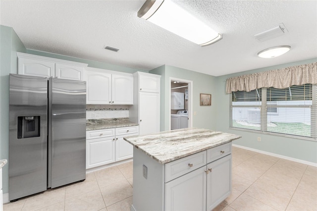 kitchen with backsplash, stainless steel refrigerator with ice dispenser, white cabinetry, and washer and clothes dryer