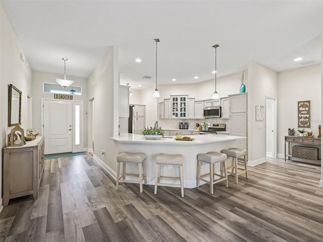 kitchen with a kitchen breakfast bar, stainless steel appliances, pendant lighting, and white cabinetry