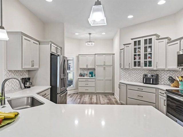 kitchen featuring gray cabinetry, stainless steel appliances, sink, and decorative light fixtures