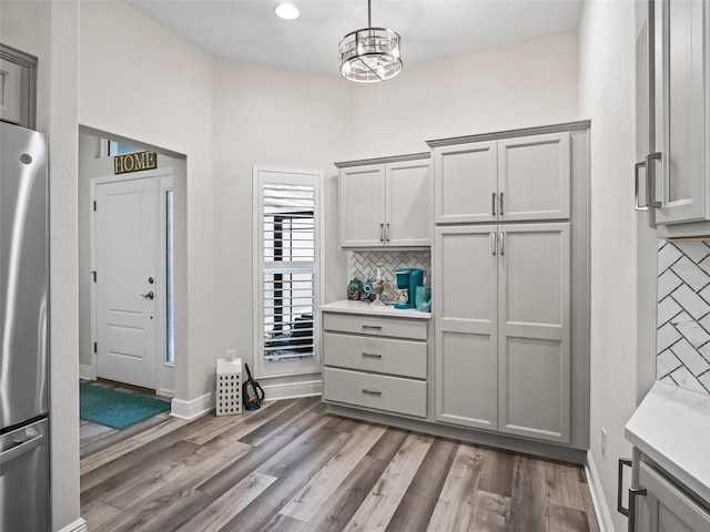 kitchen with tasteful backsplash, decorative light fixtures, stainless steel refrigerator, and gray cabinetry