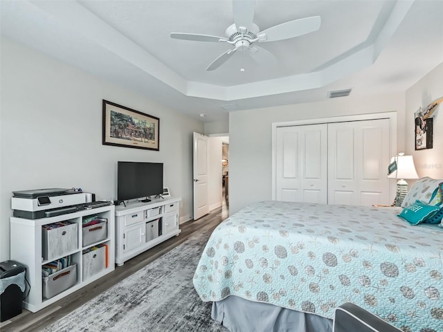 bedroom featuring ceiling fan, dark hardwood / wood-style flooring, a closet, and a raised ceiling