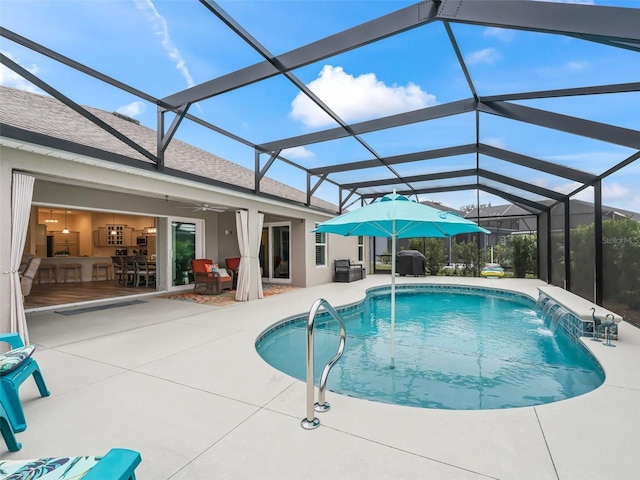 view of swimming pool featuring pool water feature, ceiling fan, a patio, and a lanai