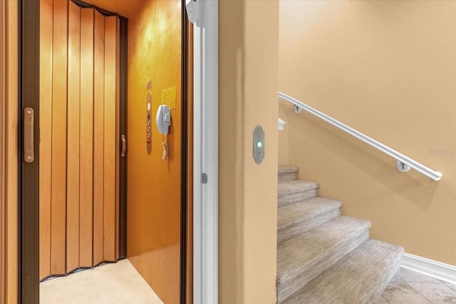 stairs featuring elevator and tile patterned flooring