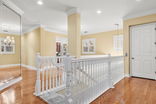 hall with ornamental molding, an inviting chandelier, and light hardwood / wood-style flooring