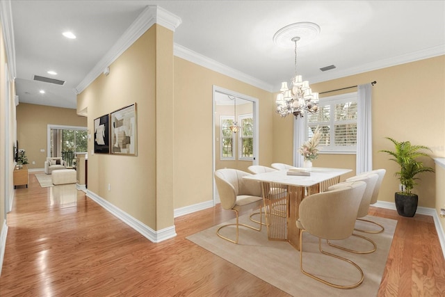 dining area with crown molding, a notable chandelier, and light wood-type flooring