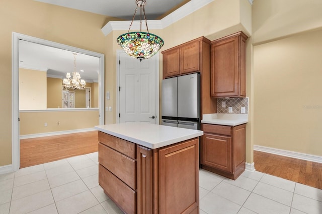 kitchen with crown molding, light tile patterned floors, stainless steel fridge, and decorative light fixtures