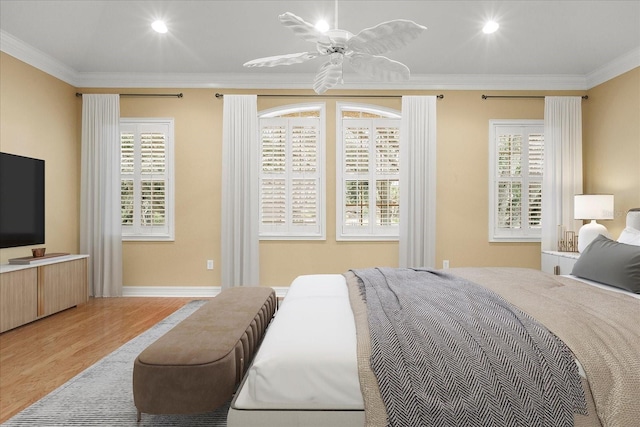 bedroom featuring hardwood / wood-style flooring, ornamental molding, ceiling fan, and multiple windows