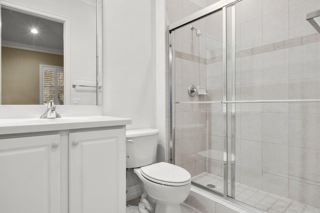 bathroom featuring ornamental molding, vanity, toilet, and a shower with door