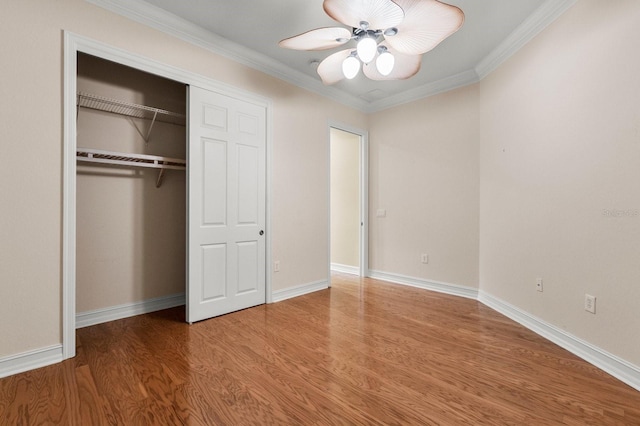 unfurnished bedroom featuring ceiling fan, ornamental molding, hardwood / wood-style floors, and a closet