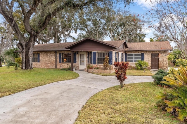 ranch-style house with driveway, brick siding, and a front lawn