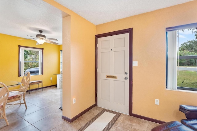 tiled foyer entrance featuring ceiling fan and a textured ceiling