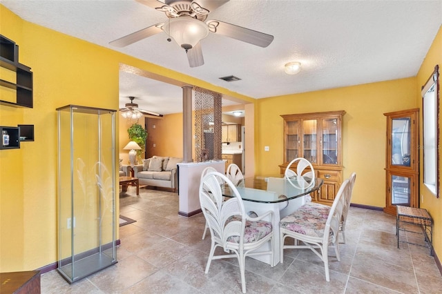 dining area with ceiling fan, decorative columns, and a textured ceiling