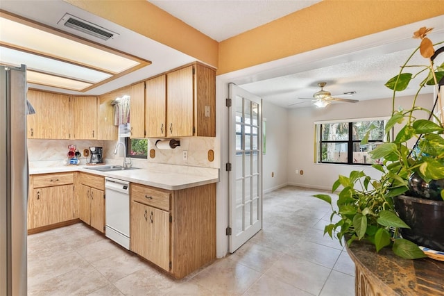 kitchen featuring tasteful backsplash, stainless steel fridge, white dishwasher, and sink