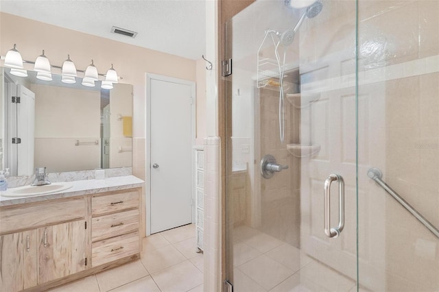 bathroom with tile patterned flooring, vanity, a textured ceiling, and walk in shower