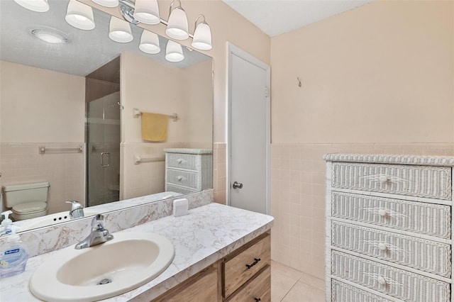 bathroom featuring vanity, a shower with shower door, tile walls, and toilet