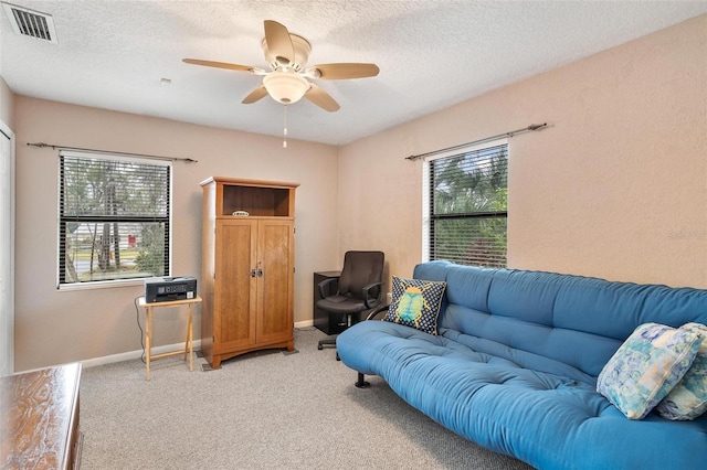 living room with ceiling fan, carpet floors, a textured ceiling, and a wealth of natural light