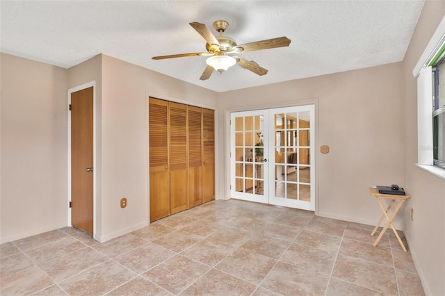 interior space with a textured ceiling, a closet, ceiling fan, and french doors