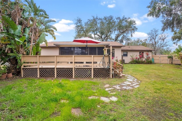 rear view of house featuring a wooden deck and a yard