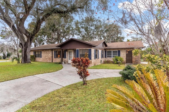 ranch-style house with a front yard, concrete driveway, and brick siding