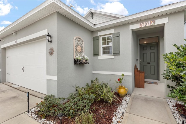 doorway to property with an attached garage and stucco siding