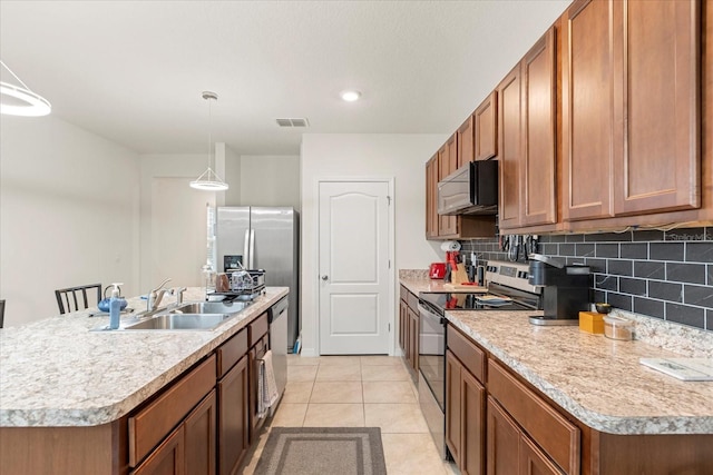 kitchen with stainless steel appliances, an island with sink, pendant lighting, sink, and light tile patterned flooring