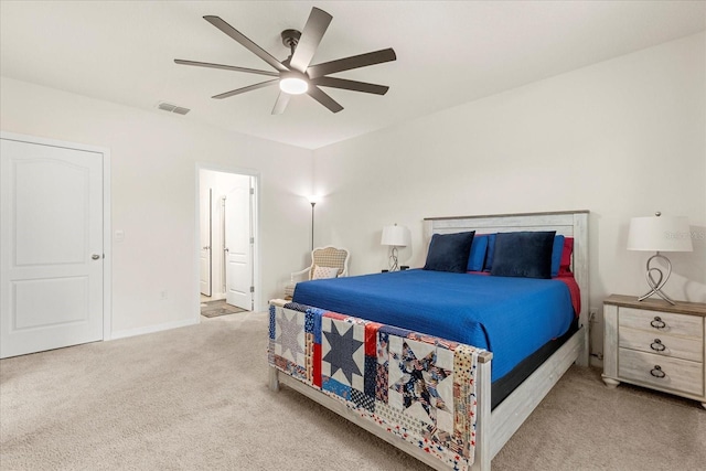 bedroom with connected bathroom, light carpet, and ceiling fan